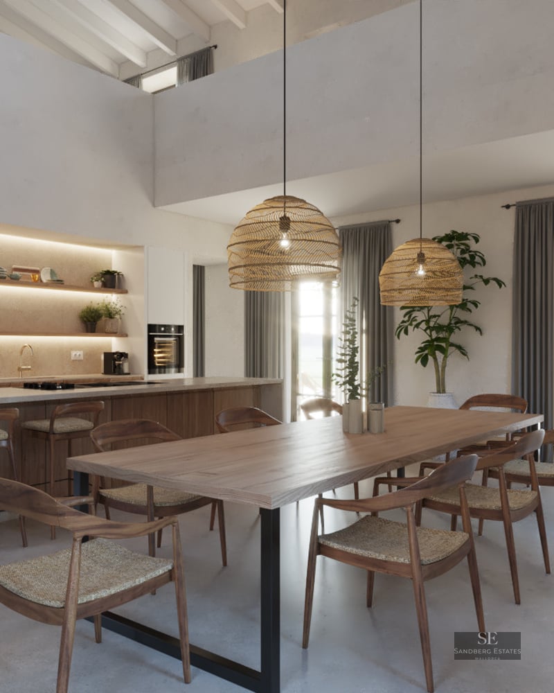 Spacious dining area with a long wooden table, wicker pendant lights, and a modern open-plan kitchen in the background.