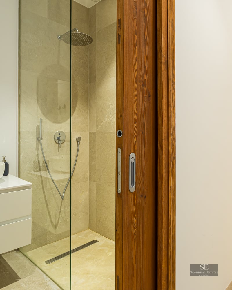 Contemporary bathroom featuring a stone walk-in shower, white vanity with vessel sink, and a sliding wooden door.