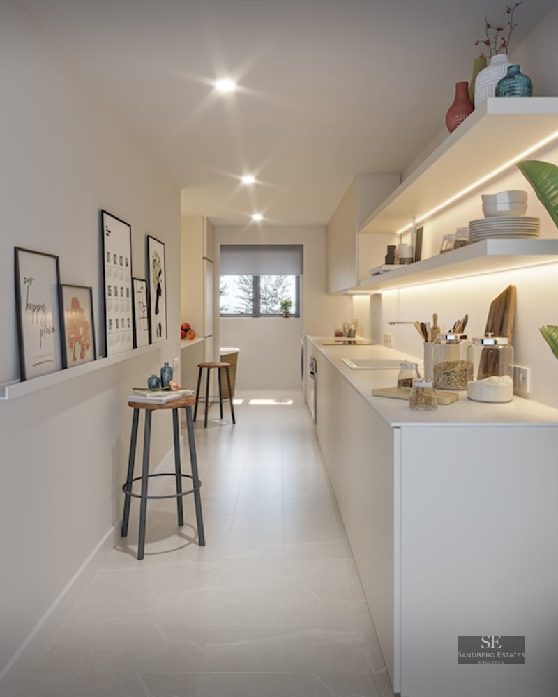 Bright, narrow modern kitchen with white cabinets, illuminated open shelves, minimalist stools, and indoor plants.