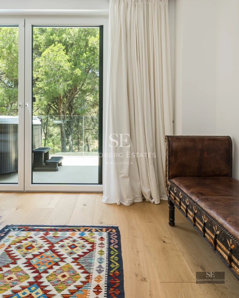 View of infinity pool surrounded by lush greenery. Modern architecture, warm lighting and high-end materials.