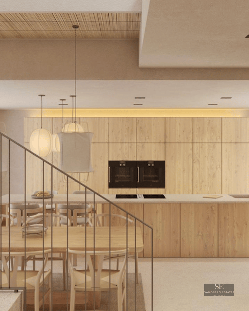 View of a modern kitchen with a wood island, dining area with Wishbone chairs, and a minimalist stone staircase.
