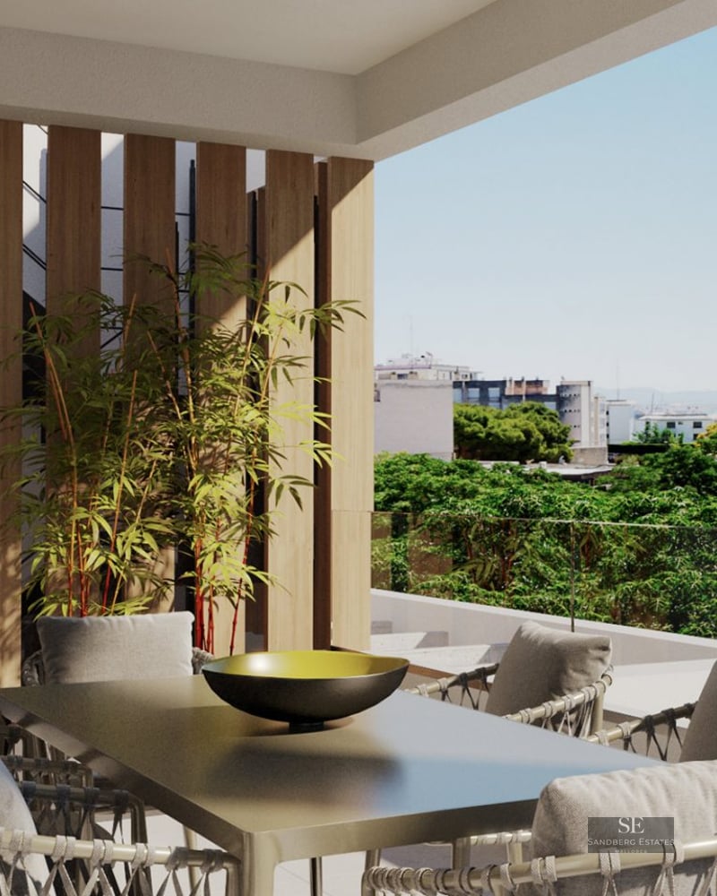 Covered terrace featuring a modern dining table, woven chairs, wood slat wall, and glass railing overlooking the city.