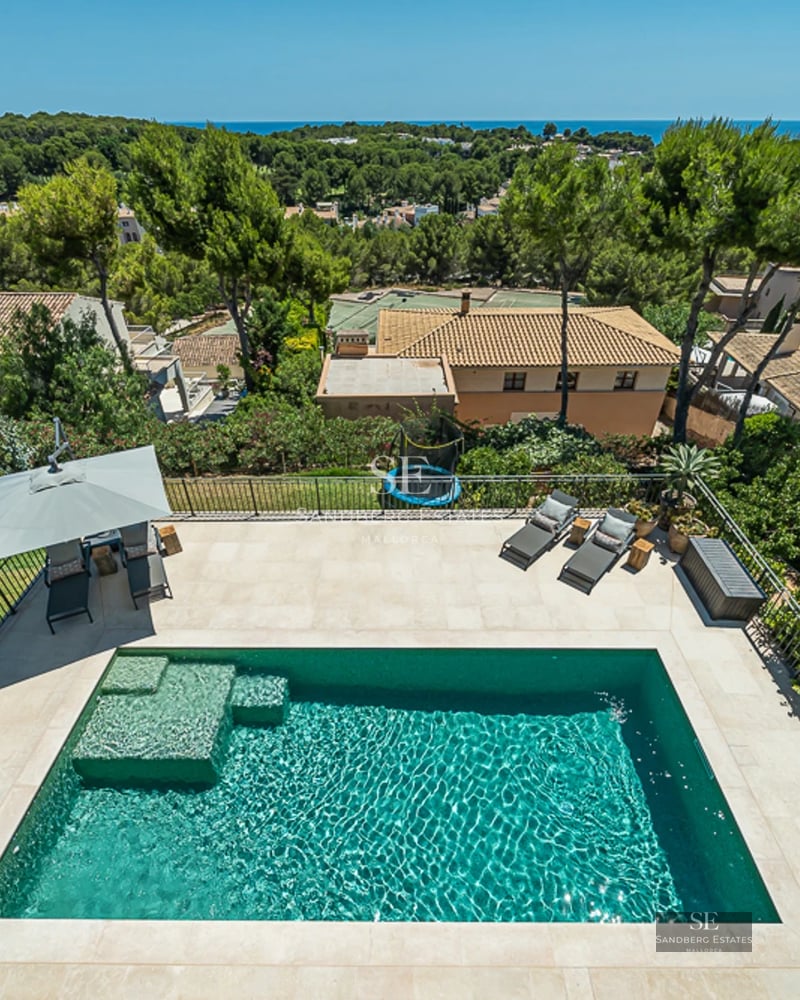 Vaste piscine avec vue, entourée de verdure. Design moderne, transats et parasols. Façade élégante et minimaliste.