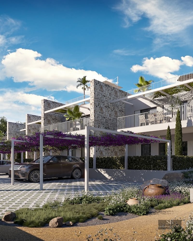 Luxury stone building with white pergolas covered in purple flowers over a modern parking area and garden path.