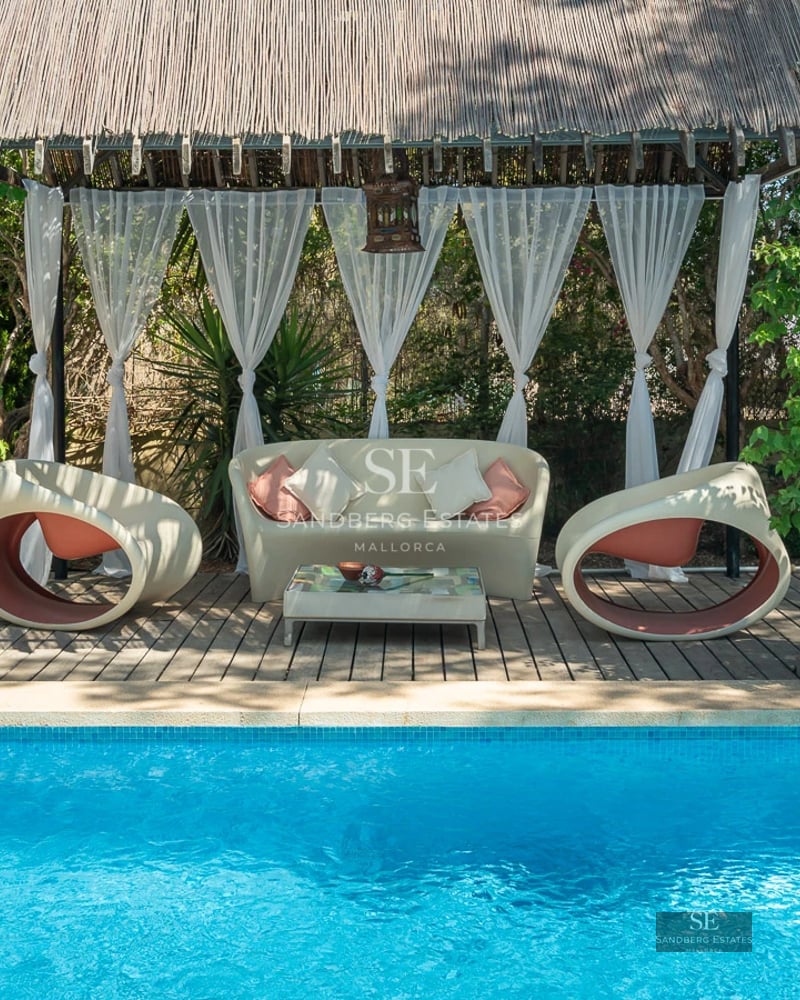 View of pool with sun loungers, lush garden, and modern facade. Minimalist architecture with large windows and neutral colors.