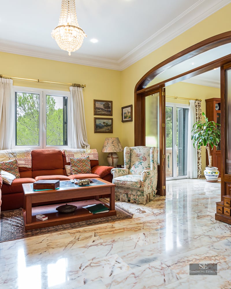 Elegant living room with terracotta sofas, polished marble flooring, a fireplace, and a large wooden archway.