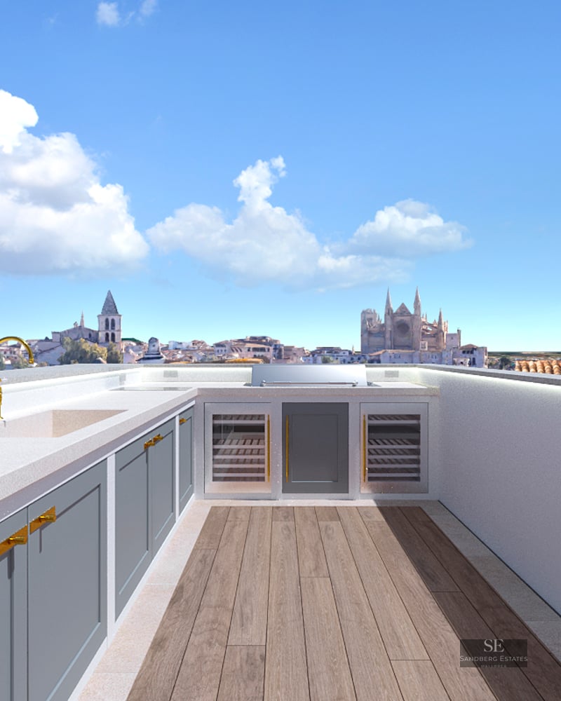 Rooftop kitchen with grey cabinets, gold faucet, and a view of a cathedral under a blue sky.