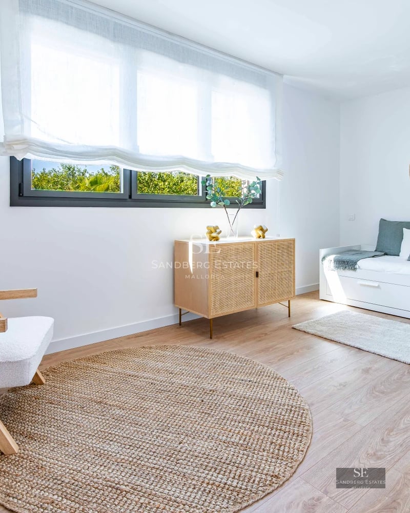 Living room view with floor-to-ceiling windows overlooking the sea. Modern design, natural light, and neutral tones. Beige sofa, rug, and minimalist decor.