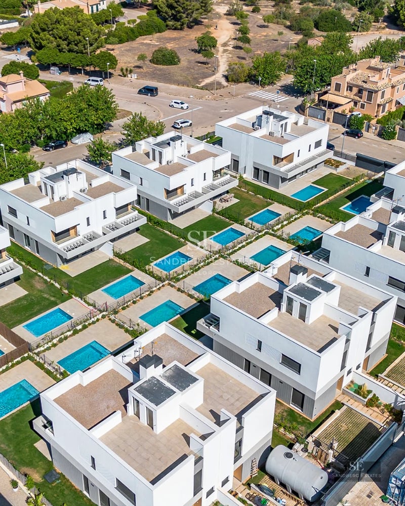 Exterior of modern villa with reflecting pool, minimalist design, and large windows. Green landscape and blue sky.