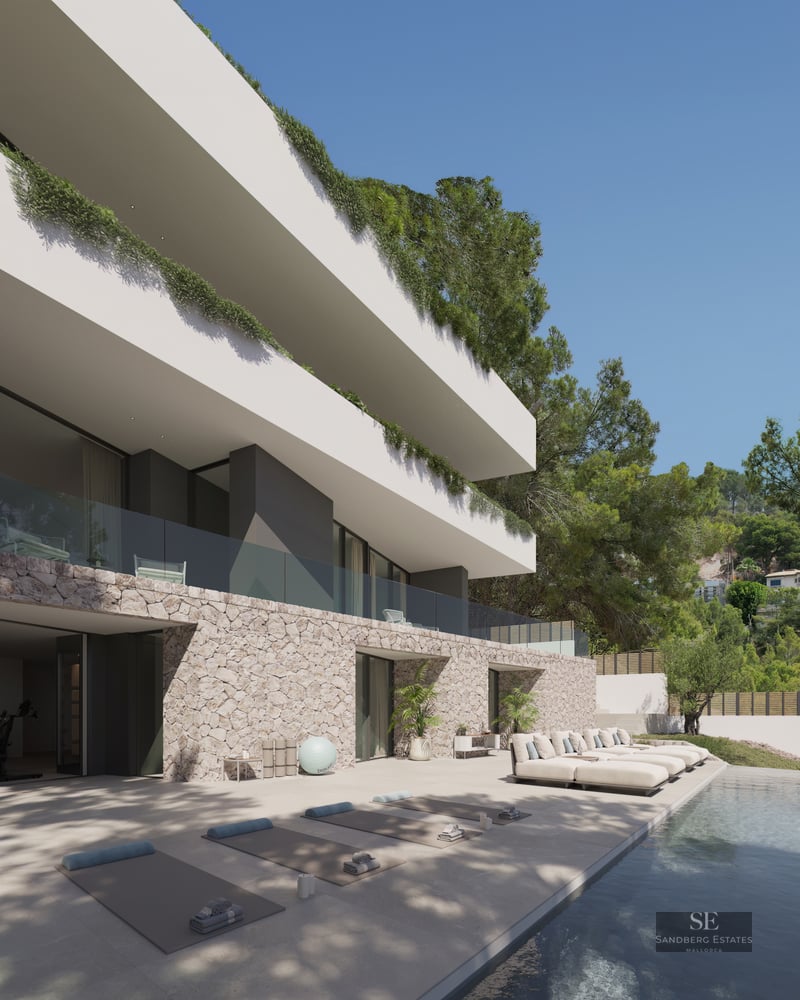 Pool terrace with sun loungers and yoga mats in front of a modern stone and white villa.