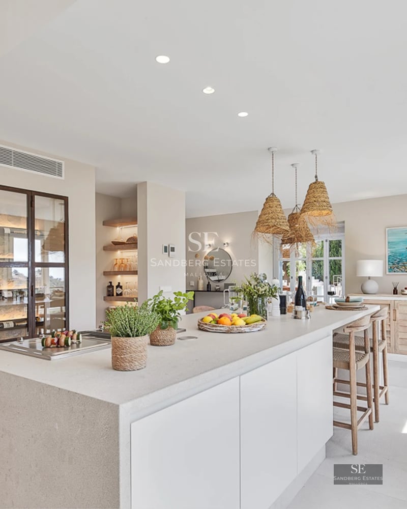 Spacious living room with large windows, light wood floors, and minimalist decor. Panoramic sea views from the balcony.