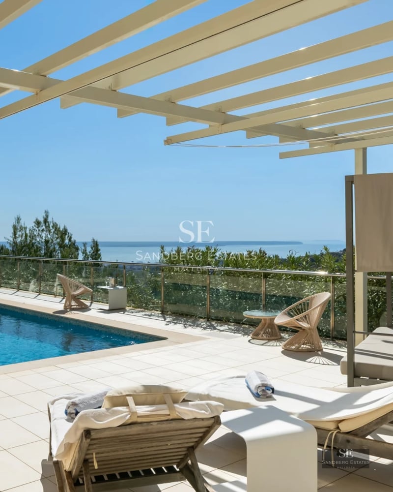 Spacious living room with large windows overlooking the pool. Modern sofas, warm lighting, and minimalist design.
