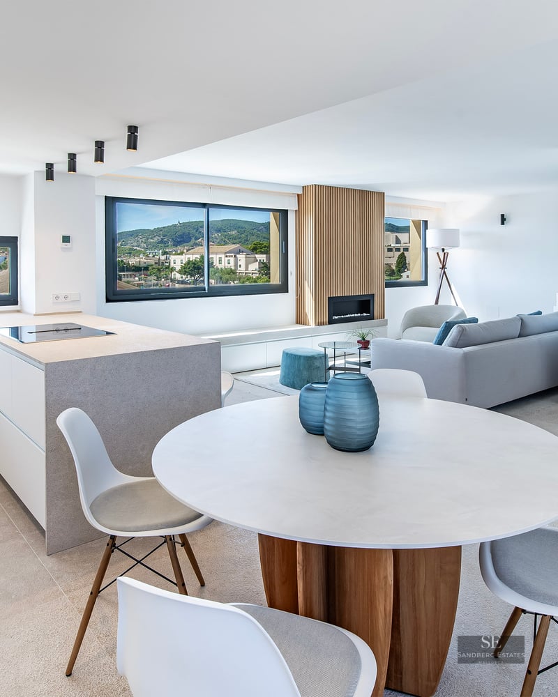 Bright open-plan interior featuring a dining area, modern kitchen island, and living room with scenic town views.