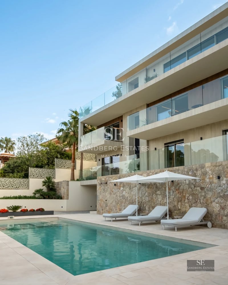 Exterior view of a modern house with a pool, manicured gardens, and large windows reflecting natural light. Minimalist and elegant design.