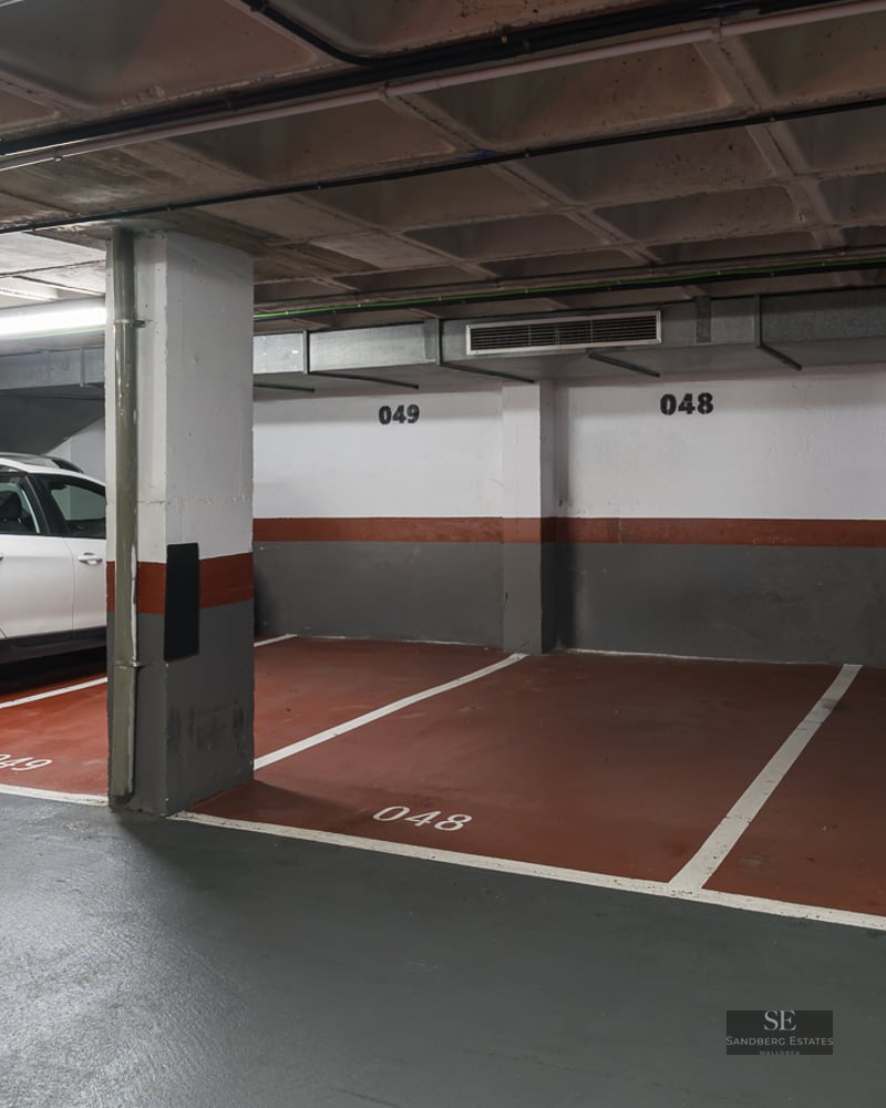 Indoor parking garage with numbered spaces and a white SUV parked next to concrete pillars.