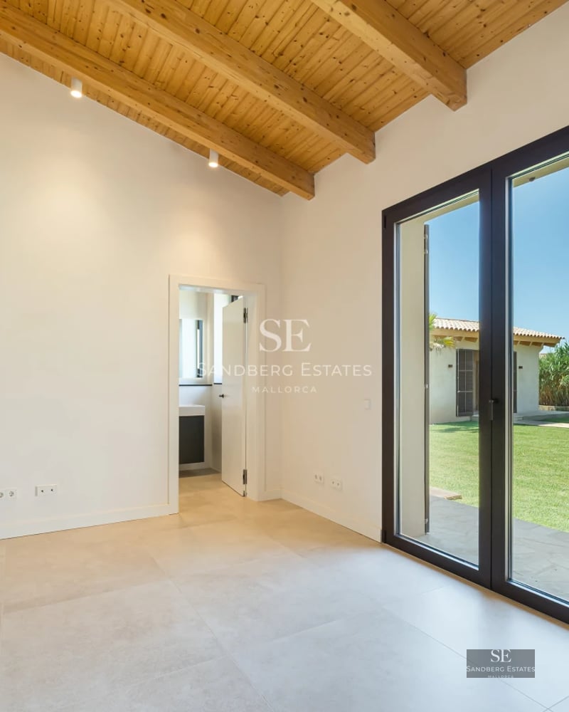 View of a modern villa with reflecting pool, large windows, and minimalist design. Lush vegetation surrounding.