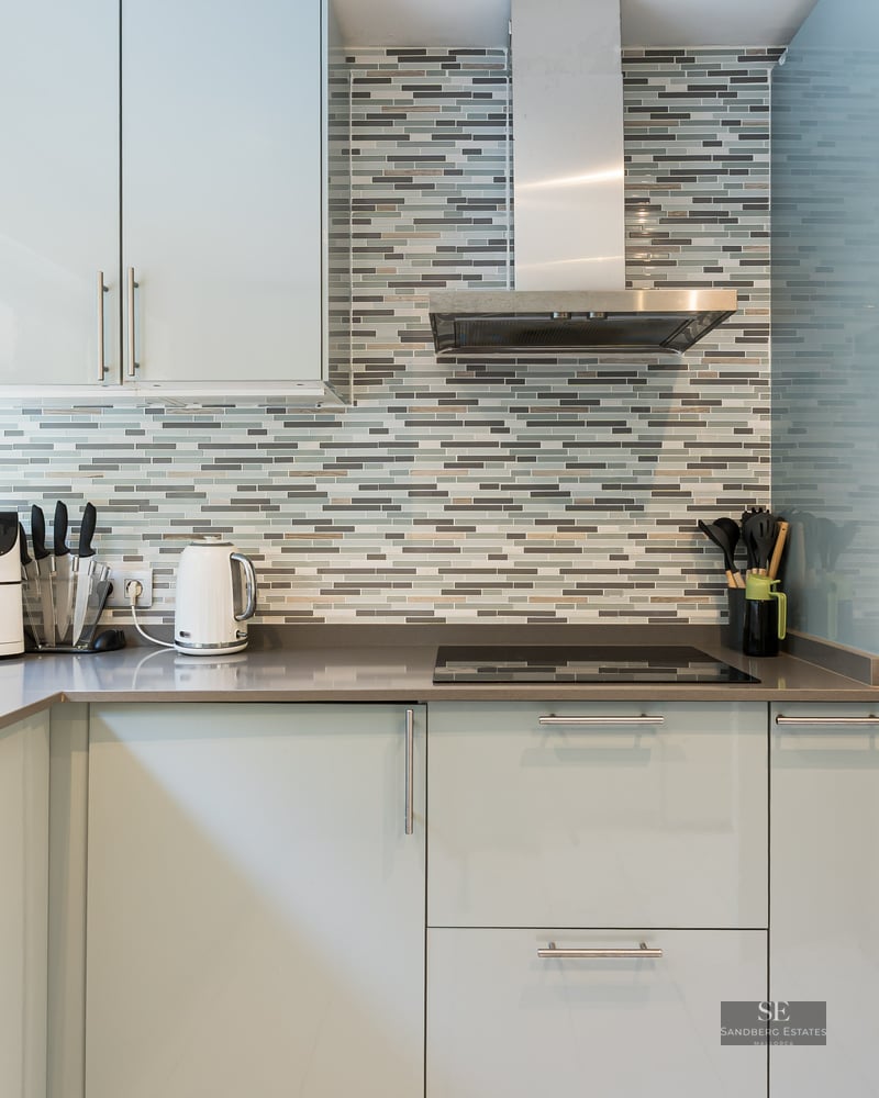 Cuisine moderne avec des armoires bleu clair, des plans de travail gris et une crédence en mosaïque.