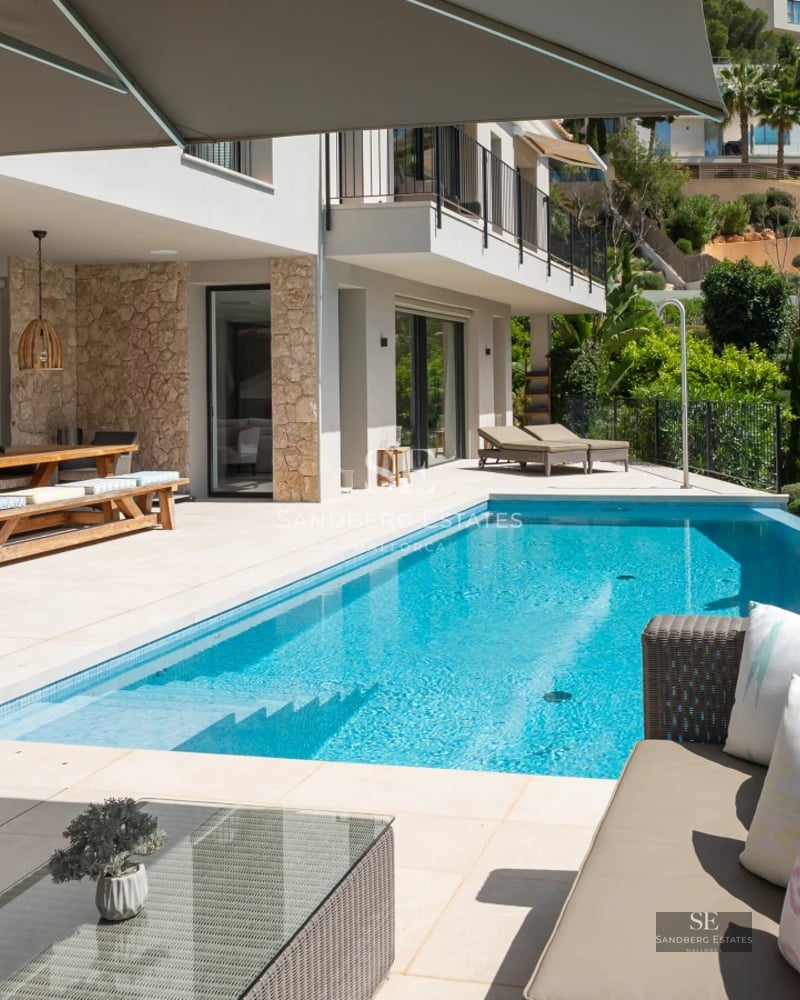 Panoramic view of infinity pool, surrounded by greenery and modern architecture. Natural lighting and serene atmosphere.