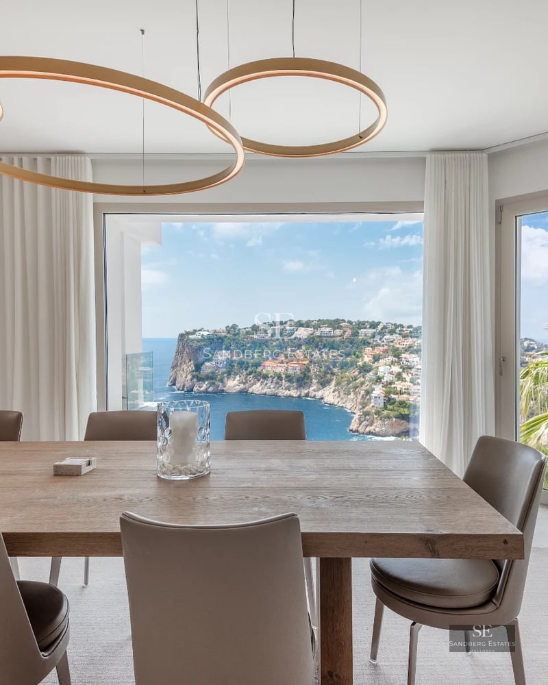 Spacious living room with floor-to-ceiling windows, modern sofas, coffee table, and panoramic sea views. Elegant and bright design.