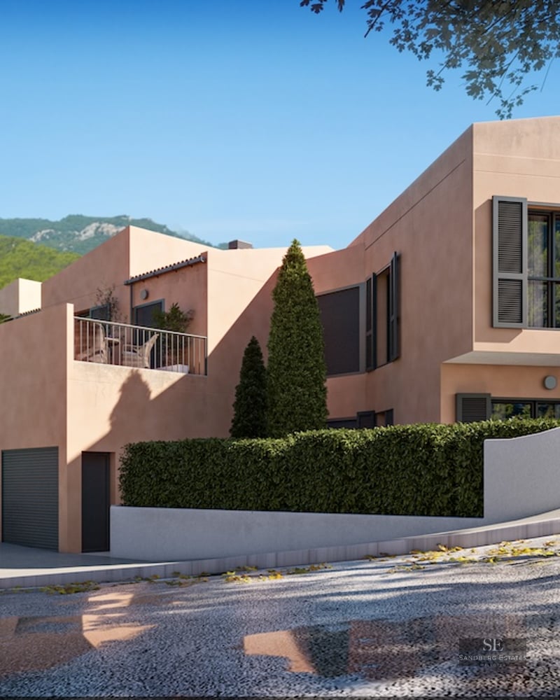 Modern peach-colored villa with dark shutters, terrace, and lush greenery against a mountainous background.
