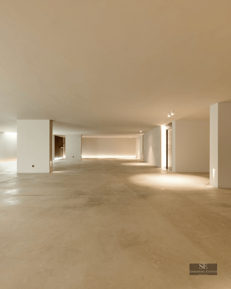 Large minimalist interior space with polished concrete floors, white pillars, and indirect LED floor lighting.