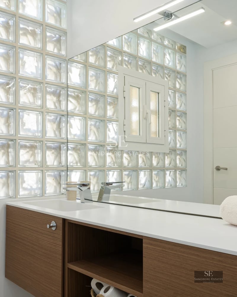 Spacious living room featuring floor-to-ceiling windows offering panoramic sea views, light wood floors, and modern neutral-toned furniture.