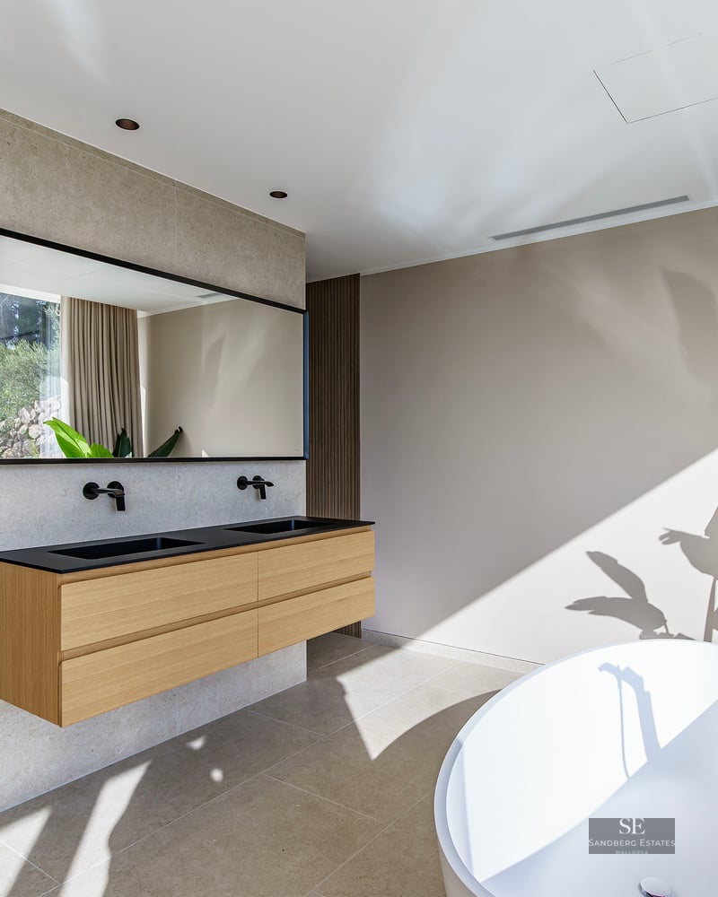 Spacious master bathroom featuring a white freestanding tub, floating wooden double vanity, and matte black fixtures.