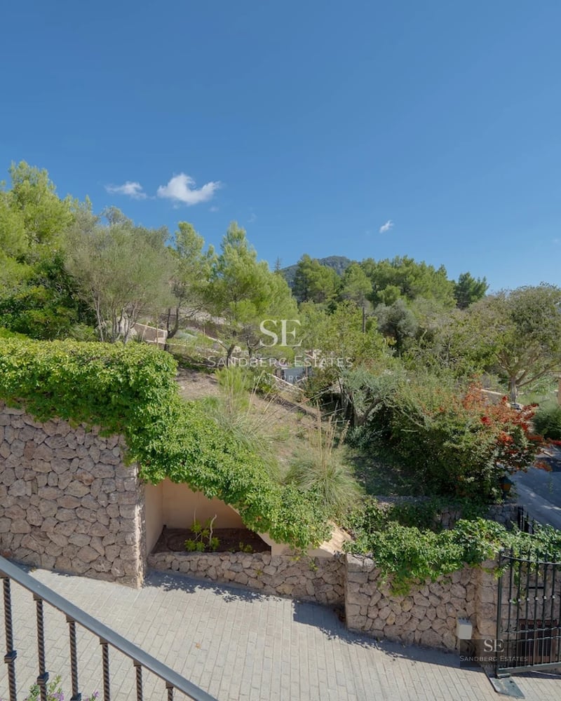 Spacious balcony with glass railing and wood flooring. Panoramic views of the sparkling blue sea. Modern outdoor furniture.