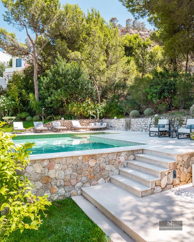 Exterior view of modern villa with swimming pool. Minimalist design, large windows and terrace with sea view. Lush garden.