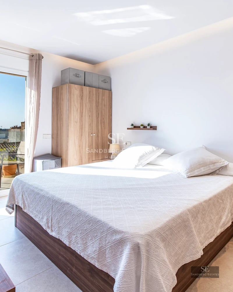 Spacious balcony with sea views, modern furniture, glass railing, wooden floor and lush vegetation.