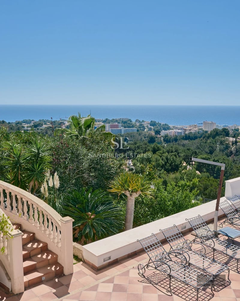 Spacious balcony overlooking the sea. Modern design, wooden floor, glass railing, and minimalist outdoor furniture.