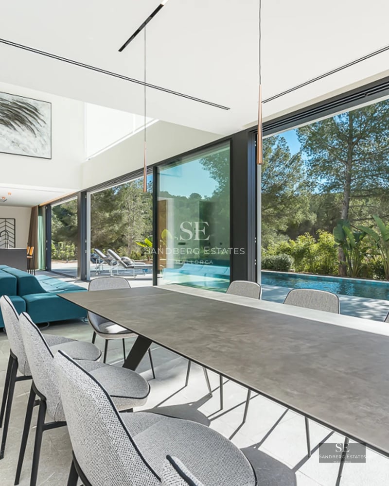 Vue extérieure d'une villa moderne avec piscine à débordement, chaises longues, pelouse et vue panoramique. Architecture minimaliste avec de grandes baies vitrées.