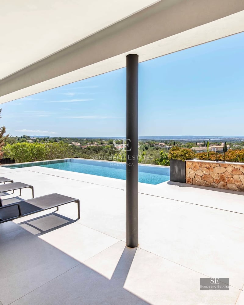 Aerial view of a modern villa with infinity pool, lush garden, and spacious terraces. Minimalist architecture and luxury finishes.