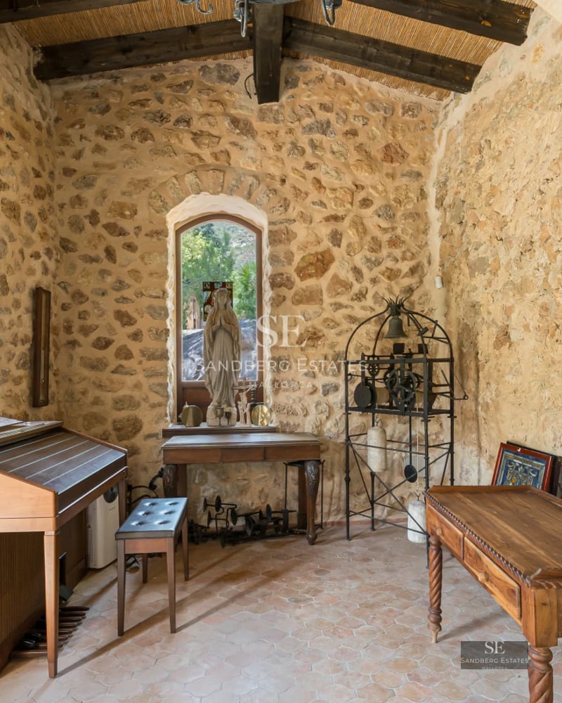 View of crystal-clear pool bordered by stone and lush vegetation, modern villa with large windows and shaded terrace. Minimalist design.