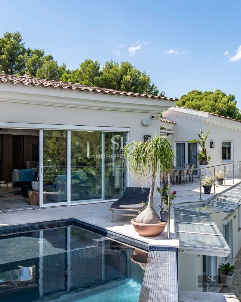 Exterior view of a modern villa with a pool. Minimalist architecture, large windows, reflective pool, lush garden. Ambient lighting.