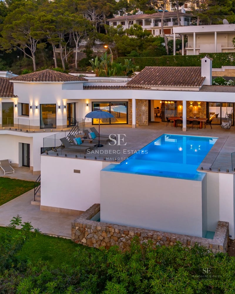 Spacious living room featuring floor-to-ceiling windows, beige sofas, a modern fireplace, and panoramic views. Abundant natural light.