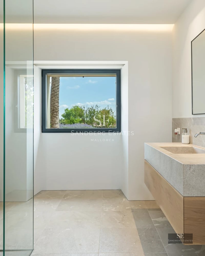 Bright living room with sea view windows. Modern design with white sofas, wooden coffee table and light tile floors.