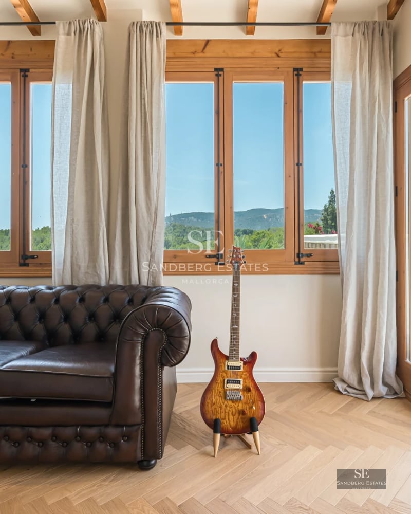 View of infinity pool with glass edge, sun loungers, and sea view from a modern terrace with lush vegetation.