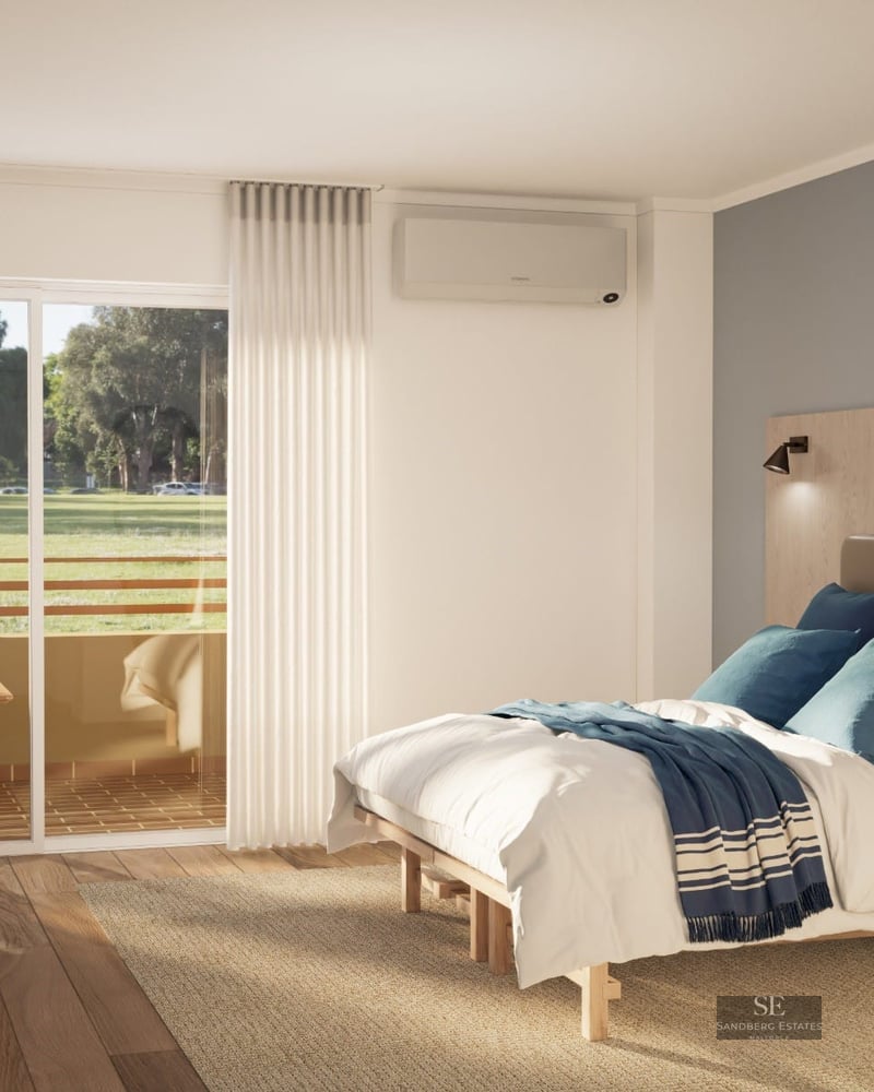 Chambre lumineuse avec parquet, lit aux accents bleus et balcon privé donnant sur des arbres.