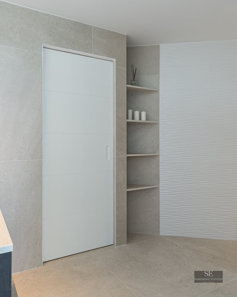 Modern bathroom featuring a marble vessel sink, backlit circular mirror, and a spacious glass-enclosed shower.