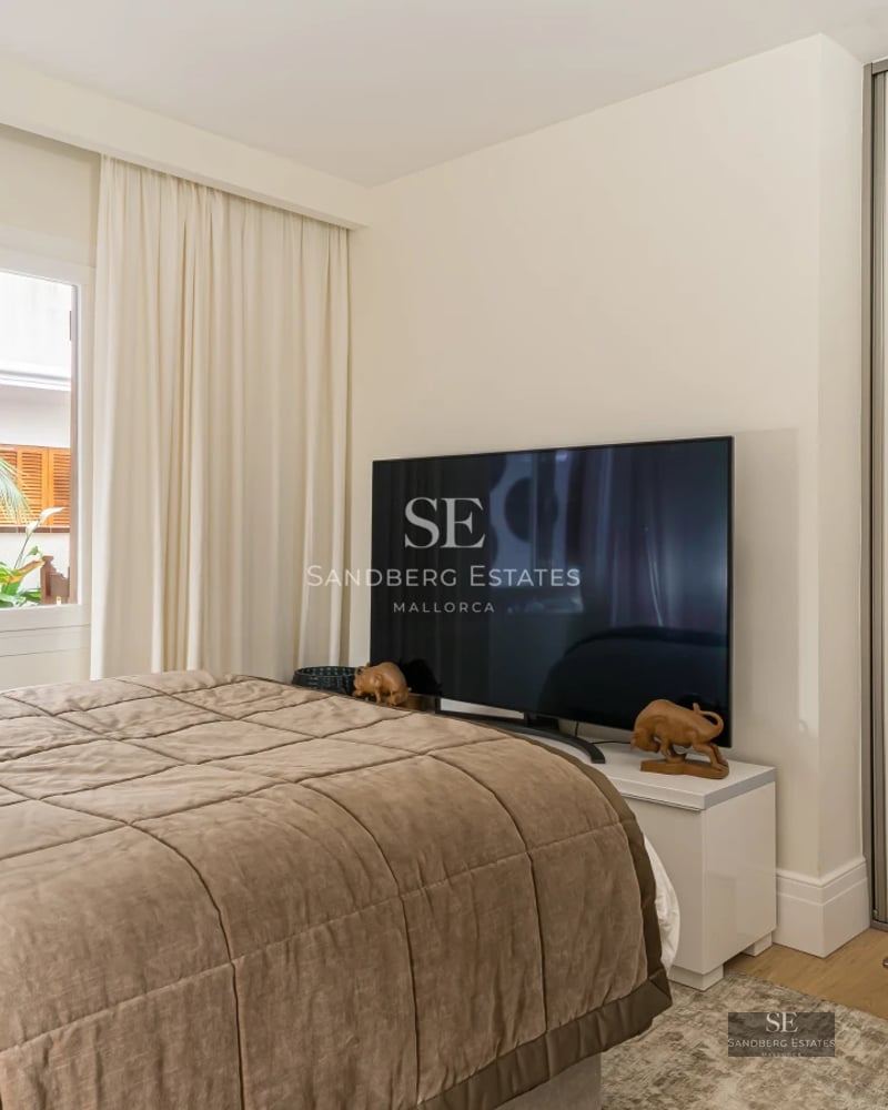 Modern living room with large windows, balcony with views, designer sofa, fireplace and light wood flooring.