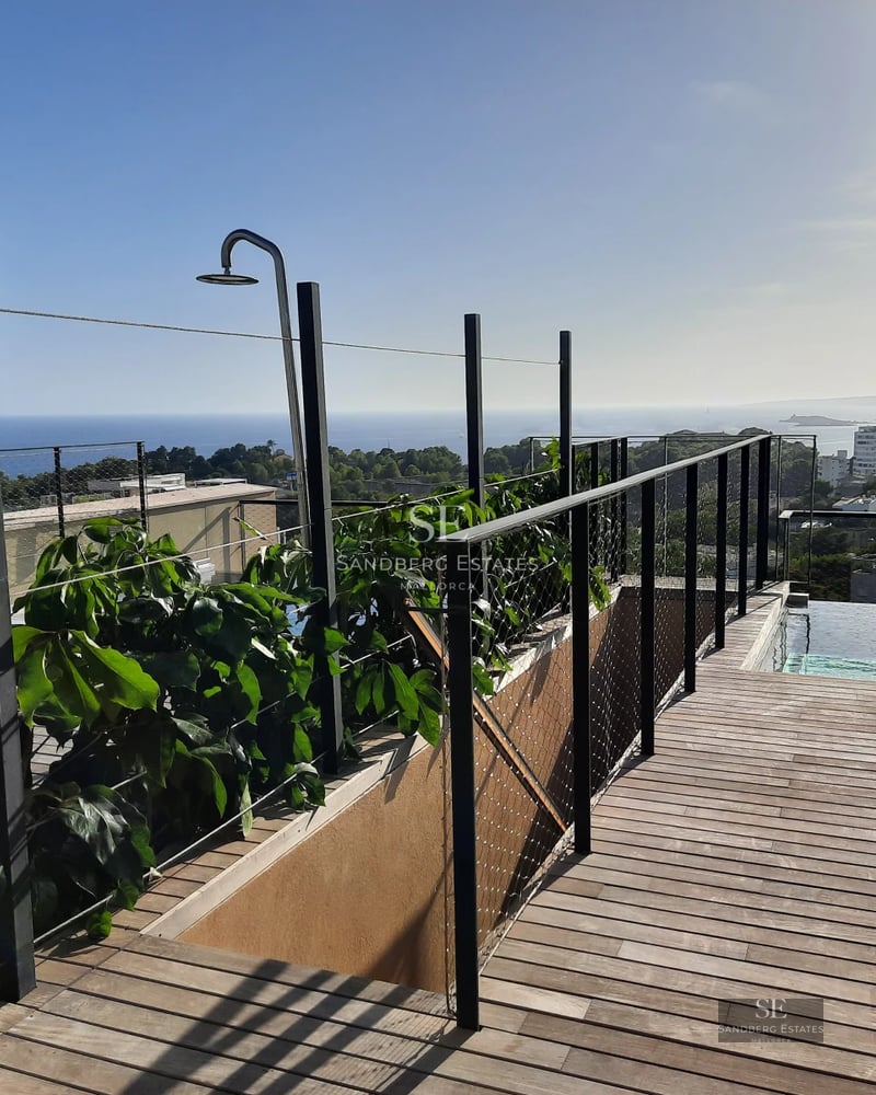 Spacious balcony with panoramic sea views from a modern apartment. Glass railing, stylish outdoor furniture.