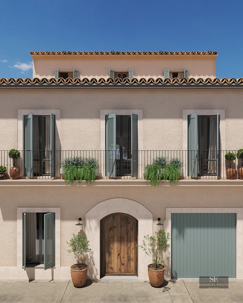 Three-story facade with beige stucco walls, sage green shutters, wrought iron balcony, and arched wooden door.