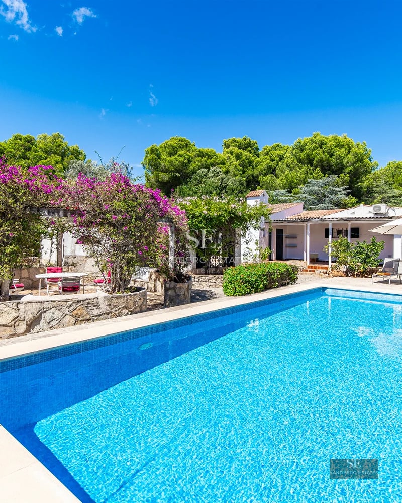 Spacious, bright living room featuring large windows, light wood floors, a modern fireplace, and panoramic sea views. Minimalist and elegant design.