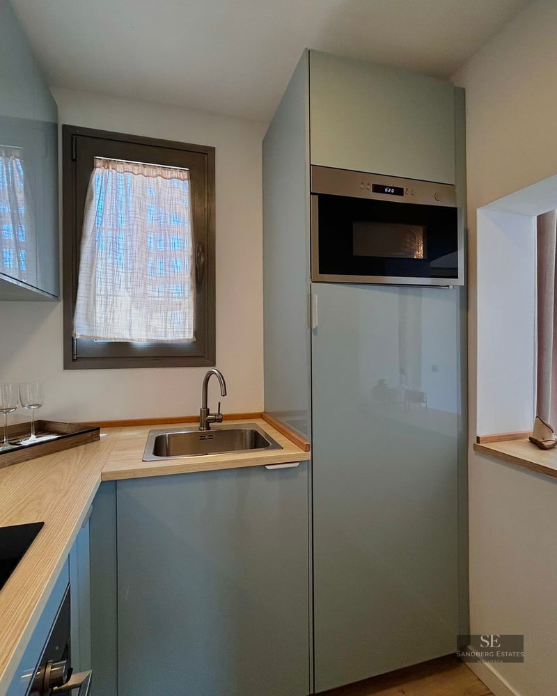 Modern kitchen with light blue cabinets, wooden countertop, stainless steel sink, and integrated microwave.