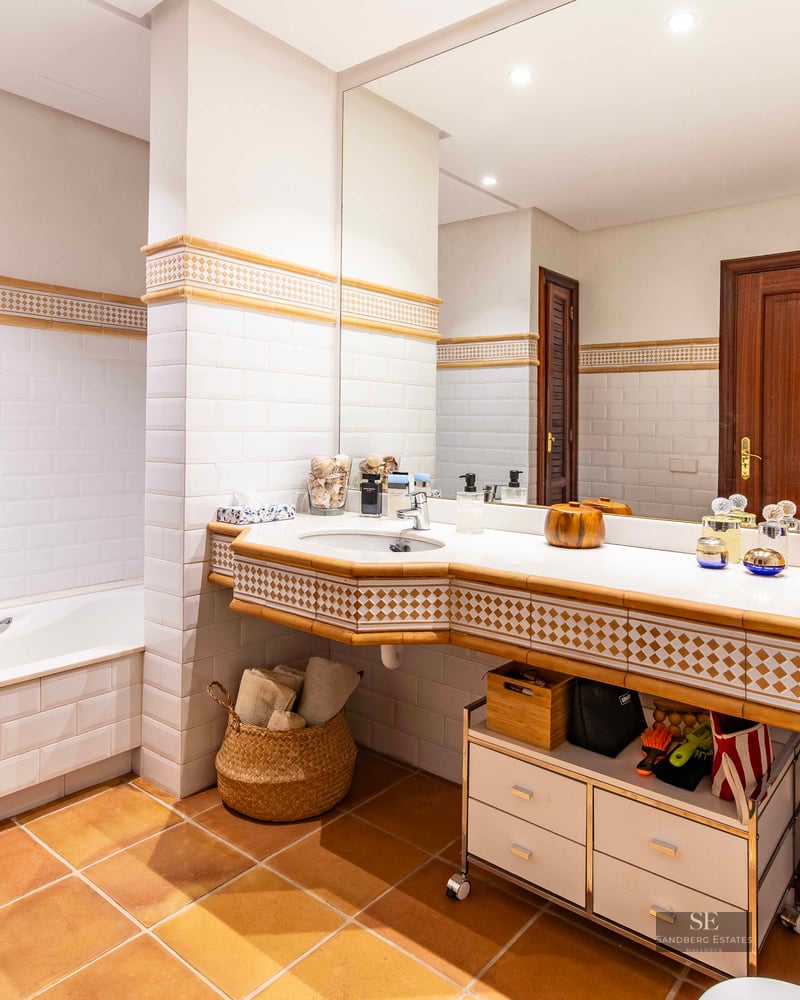 Bathroom featuring white subway tiles, terracotta floor, a built-in bathtub, and a large mirror over the vanity.