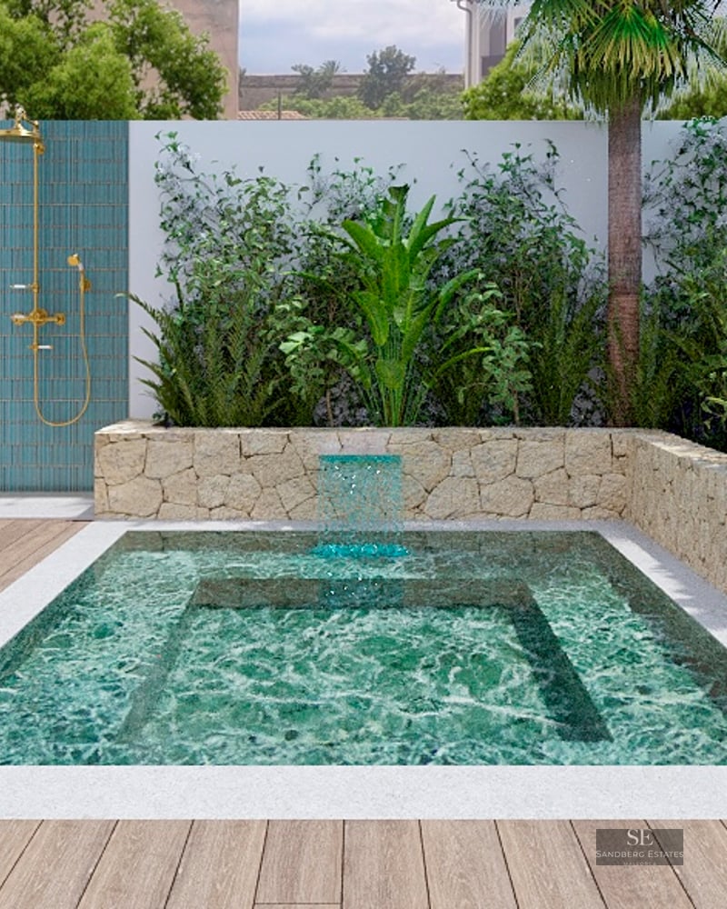Small turquoise pool with a waterfall, surrounded by stone walls and plants, next to a brass outdoor shower.