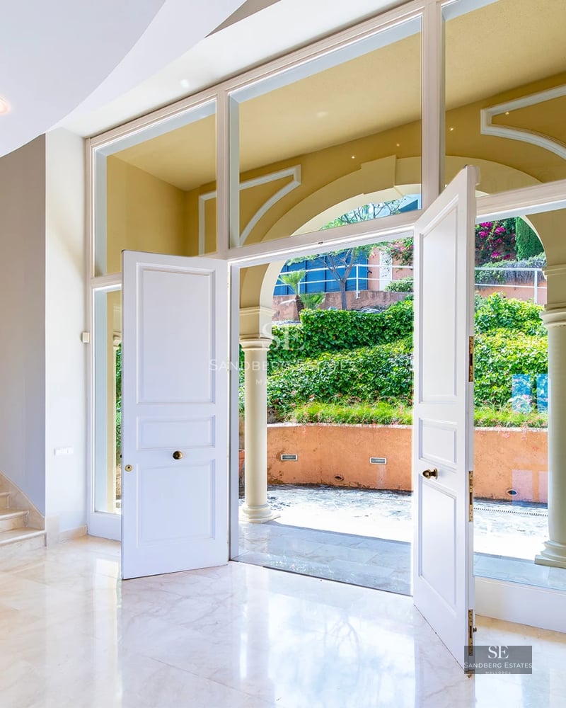 Exterior of a modern villa with infinity pool, lush garden, and spacious terraces offering panoramic sea views.