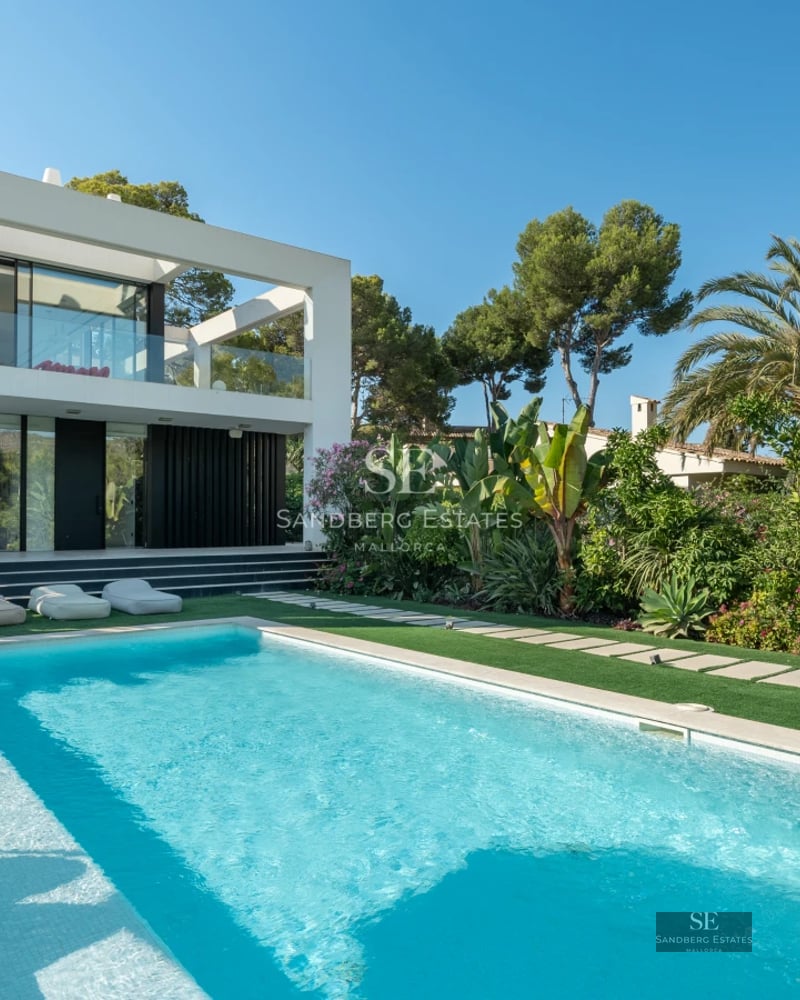 Large reflecting pool surrounded by manicured lawn. Modern facade with large windows and minimalist architecture.