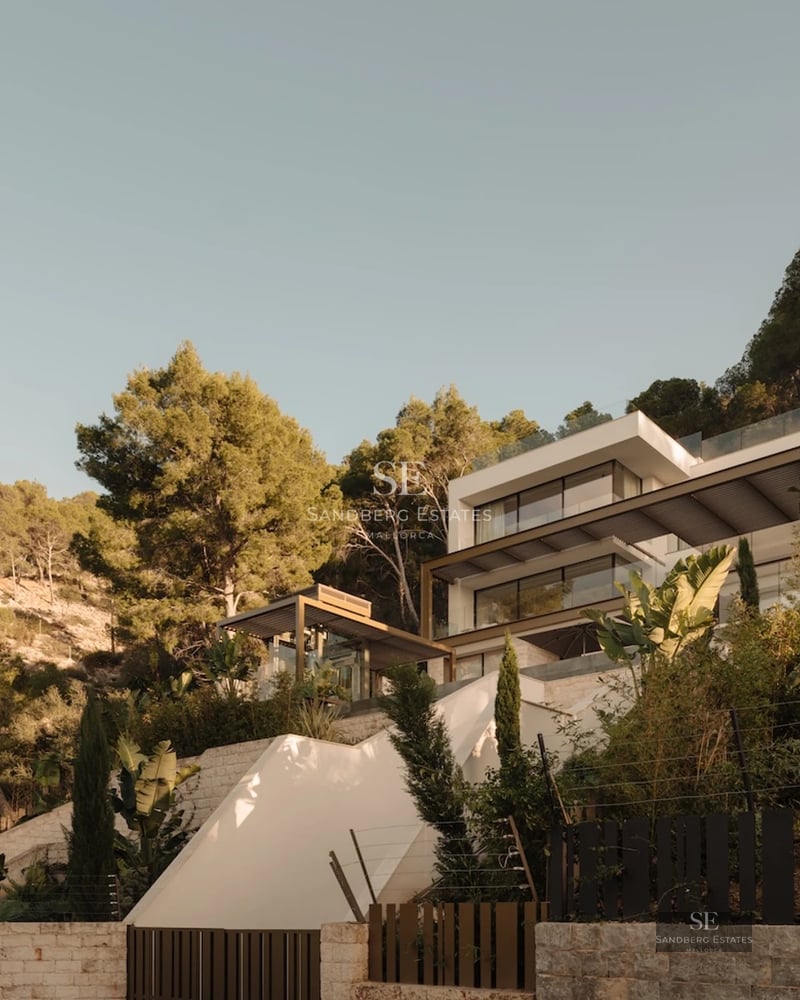 Exterior view of a luxurious house with infinity pool, manicured garden, and modern architecture. Large windows and natural light.